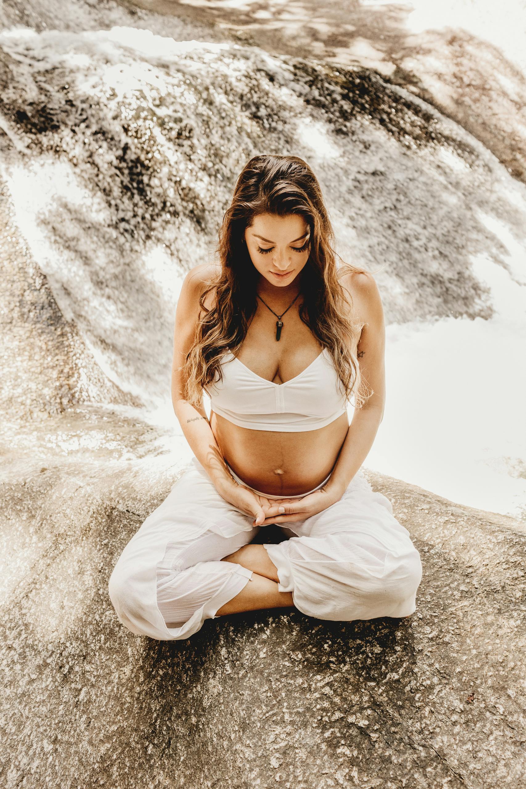 Pregnant Woman Doing Yoga with against the Backdrop of a Cascading Waterfall