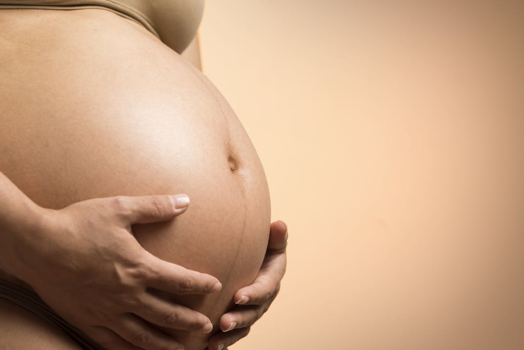 A tender close-up of a pregnant woman's hands holding her belly, symbolizing maternity and love.